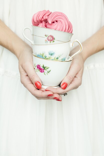 Person holding three floral ceramic teacup