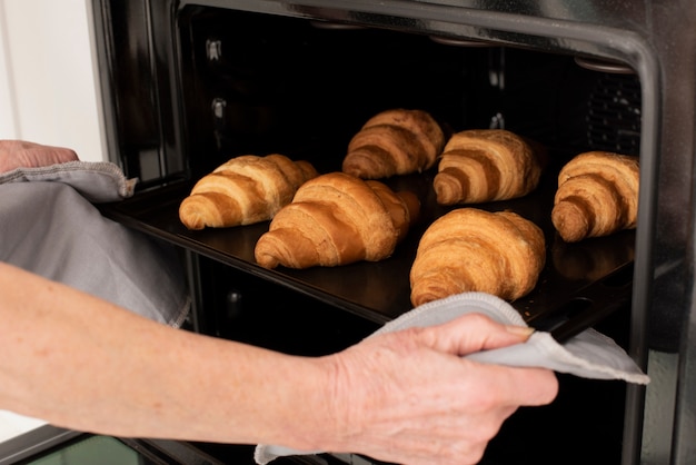 Person holding the tray with croissants in the oven