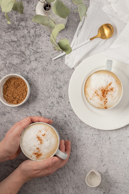 Person holding white ceramic mug with coffee