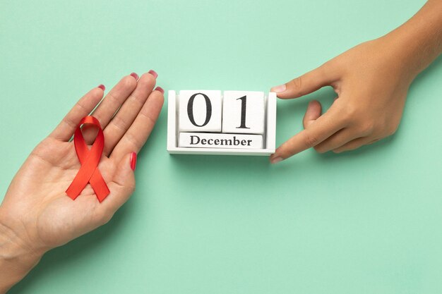 Person holding an world aids day ribbon symbol with the event date