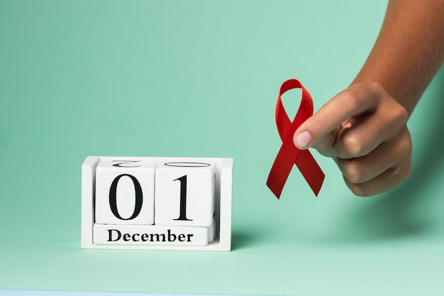 Person holding an world aids day ribbon symbol with the event date