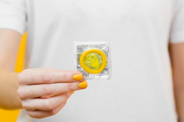 Person holding a yellow condom in  front of her