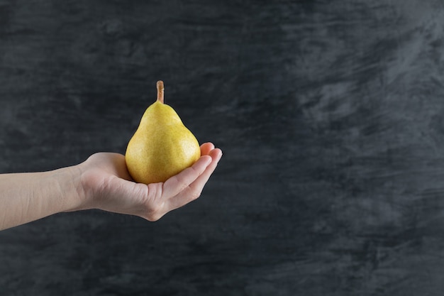 Free photo a person holding a yellow pear in the palm