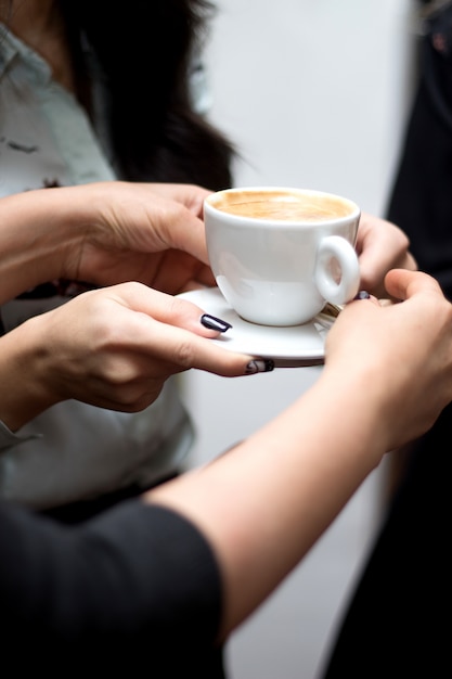 A person holds a cup of cappuccino