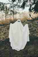 Бесплатное фото Человек в костюме призрак, стоя в лесу с поднятыми руками