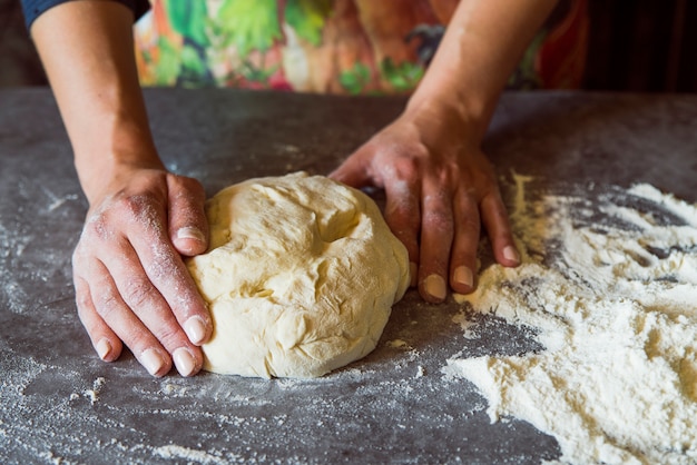 Person kneading the dough on table