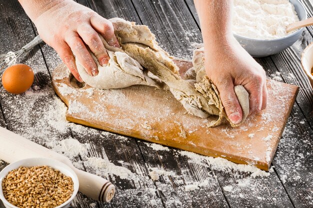 A person kneading dough with flour on chopping board