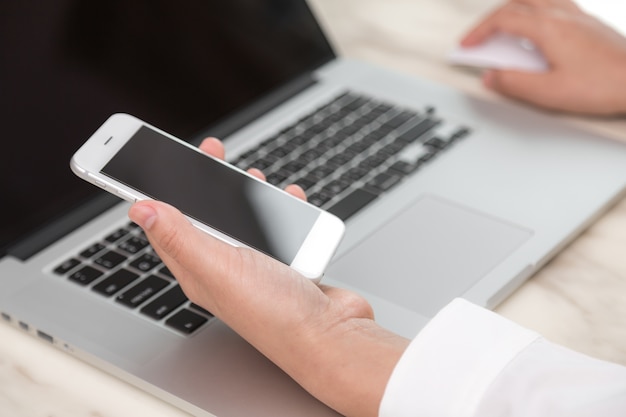 Person looking at a laptop and a mobile