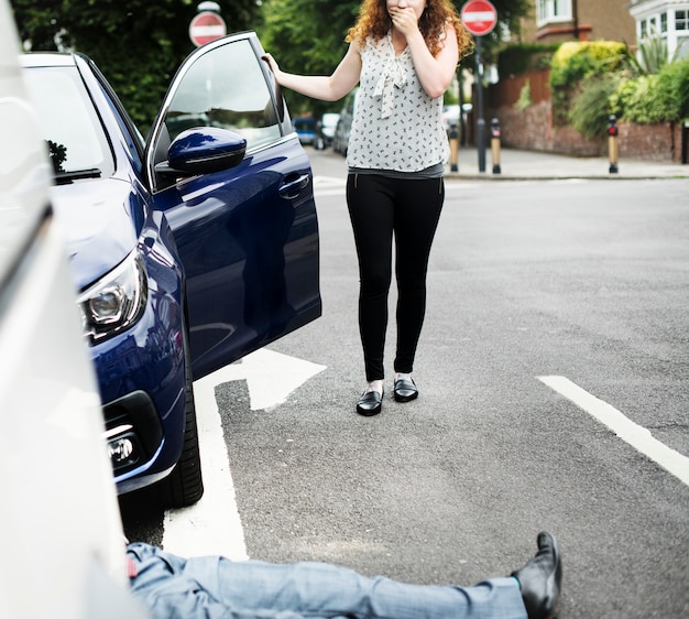 Person lying on the ground after a car accident