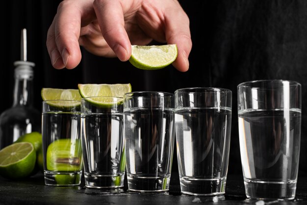 Person making cocktails with alcohol and lime