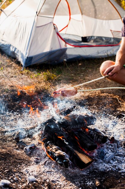 Person making sausages on fire grill