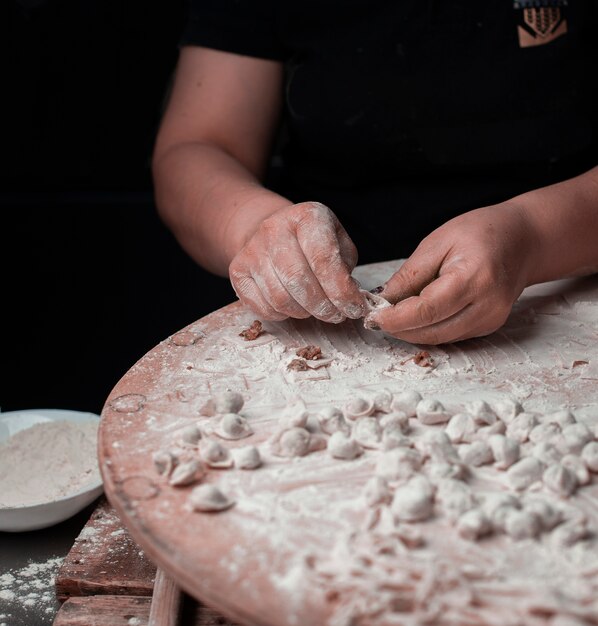 A person making turkish manti with dough.