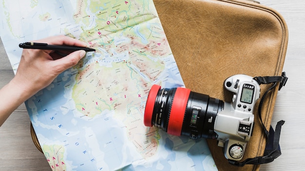 Free photo a person marking destination on map over the travel bag