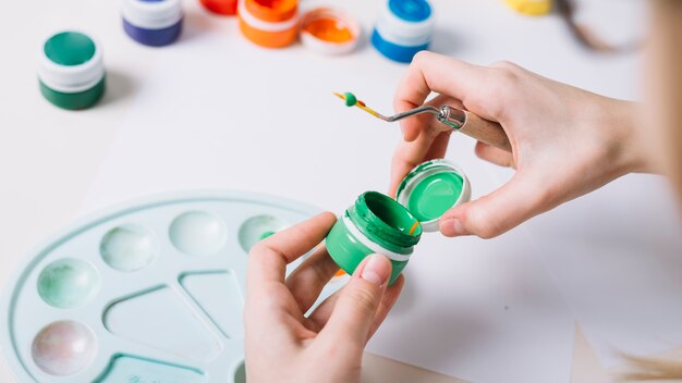 Person opening gouache can at table