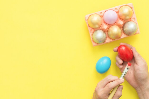 person painting colorful easter egg painted in pastel colors composition with paint brush
