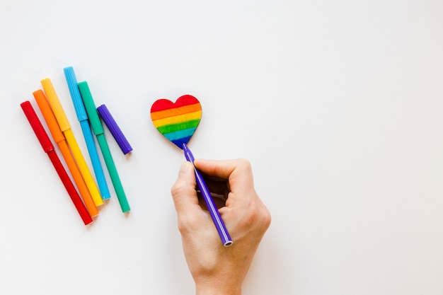 Person painting rainbow heart with felt pen