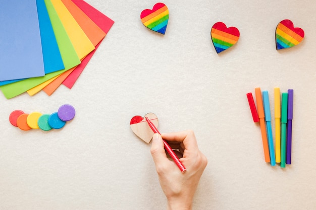 Free photo person painting rainbow heart with red felt pen