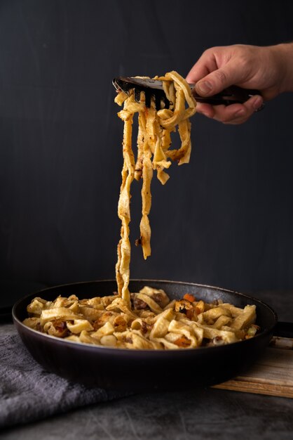 Person picking up freshly cooked pasta