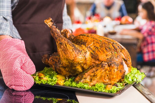 Person in pinafore holding plate with roasted ham