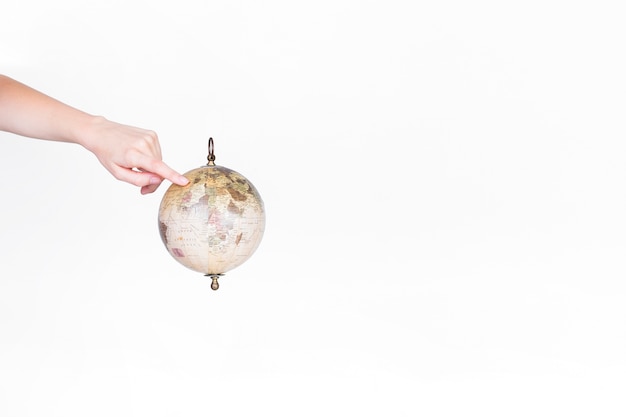 A person pointing finger at destination on globe pendulum