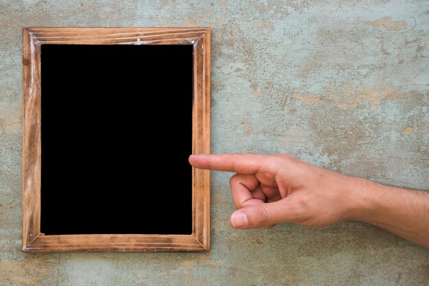 A person pointing finger on wooden blank frame over the grunge background