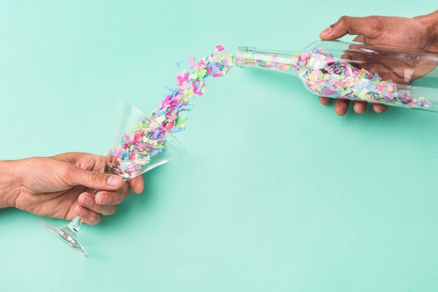 Person pouring confetti from the bottle into the glass