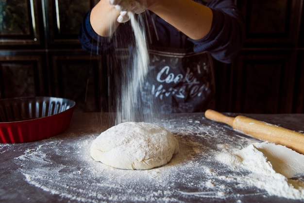 Free photo person pouring flour on dough