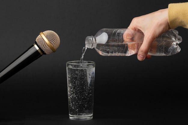Человек наливает стакан газированной воды из бутылки рядом с микрофоном для asmr
