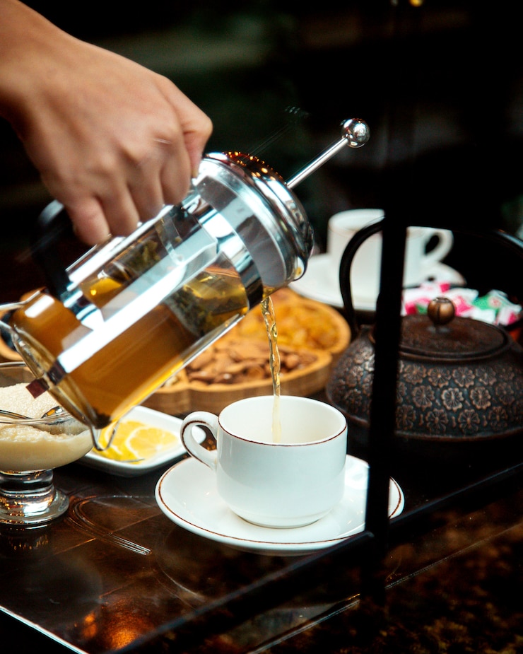 Free Photo a person pouring green tea into a cup