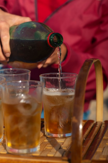 Foto gratuita persona che versa la bevanda di guaranà in vetro dalla bottiglia