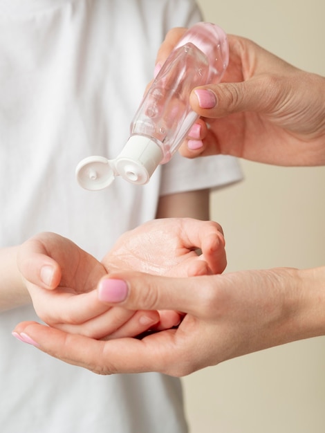 Free photo person pouring hand sanitizer in child's hands