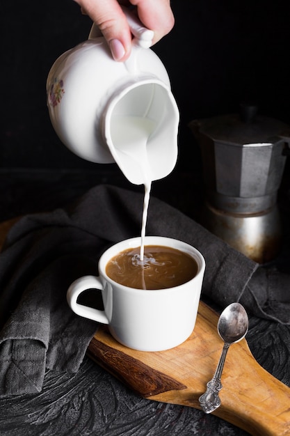 Person pouring mil in cup of coffee