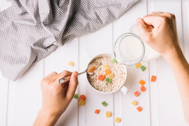 A person pouring milk in the oat with jelly candies