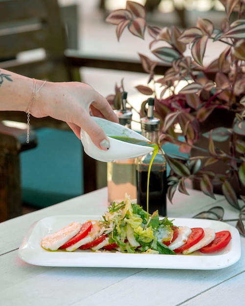 A person pouring sauce on salad