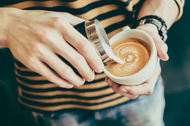 彼のコーヒーカップに砂糖を注ぐ人