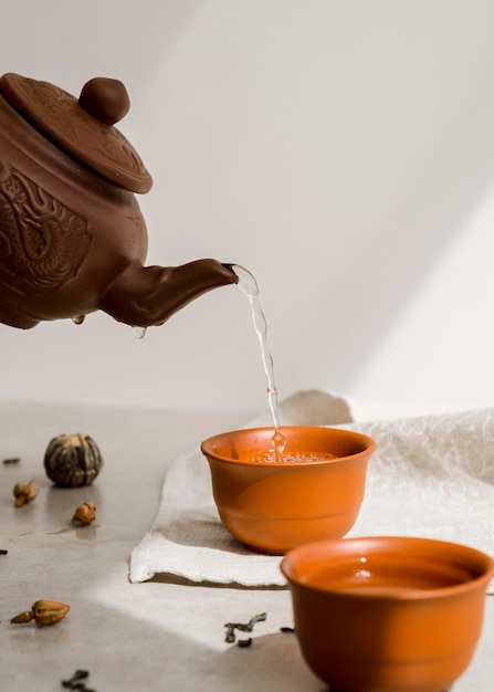 Foto gratuita persona che versa il tè dalla teiera di argilla