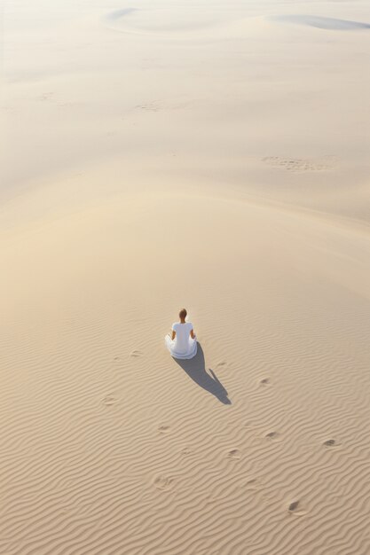 Person practicing yoga meditation in the desert
