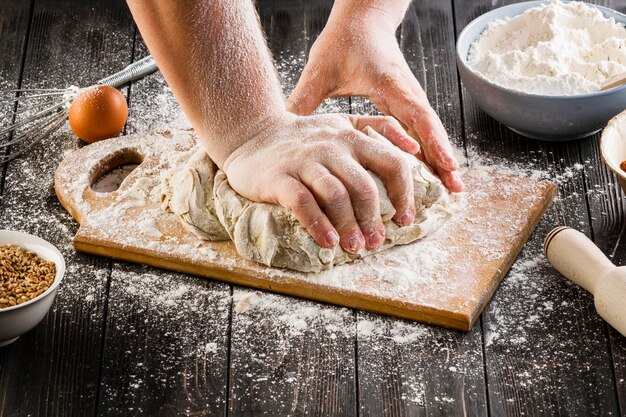 A person preparing the bread dough on chopping board