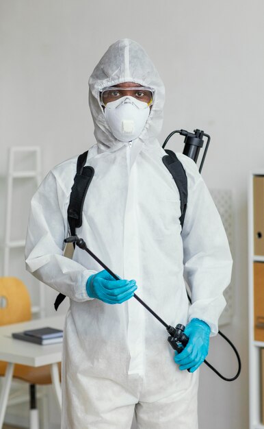 部屋を消毒する準備をしている防護服を着た人