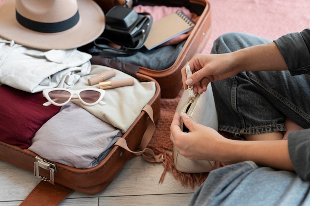 무료 사진 그녀의 휴가를 위해 여행 가방에 옷을 넣는 사람