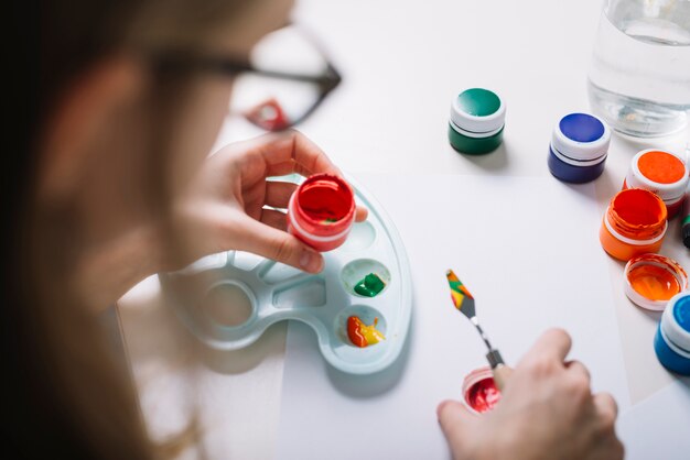 Person putting gouache on palette at table