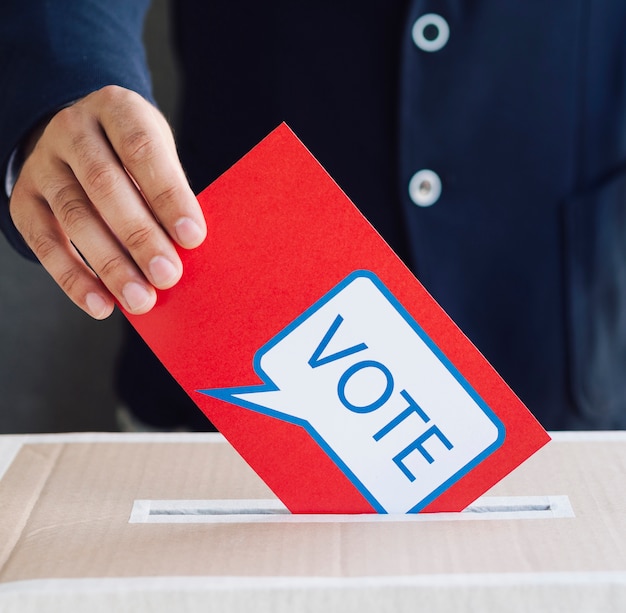 Persona che mette un voto rosso in una scatola elettorale
