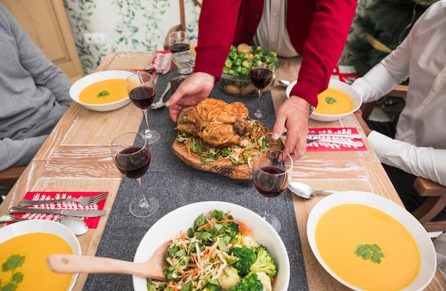 Person putting roasted chicken on festive table