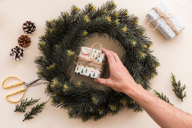 Person putting small gift box in Christmas wreath 