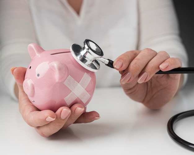 Person putting a stethoscope on a piggy bank