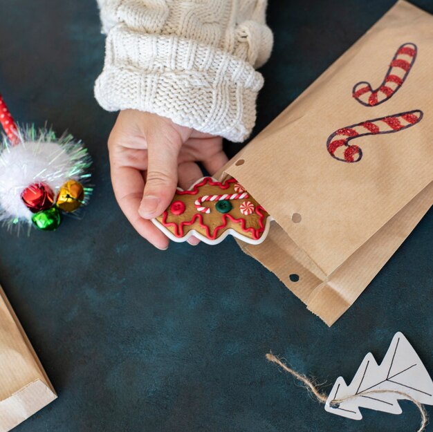Человек кладет угощение в рождественский подарочный пакет, украшенный конфетой