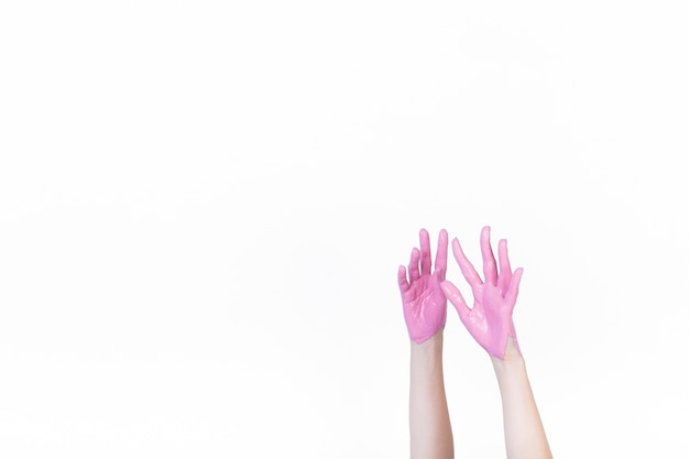 A person raising hand with pink paint over white background