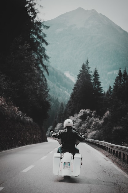 Free photo person riding white motorcycle along paved road