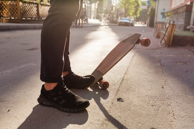 Person's feet and wooden skateboard on street