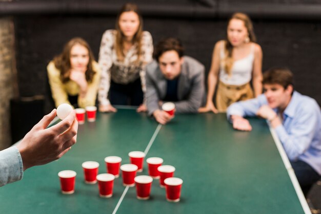 person's hand aiming ball for beer pong game